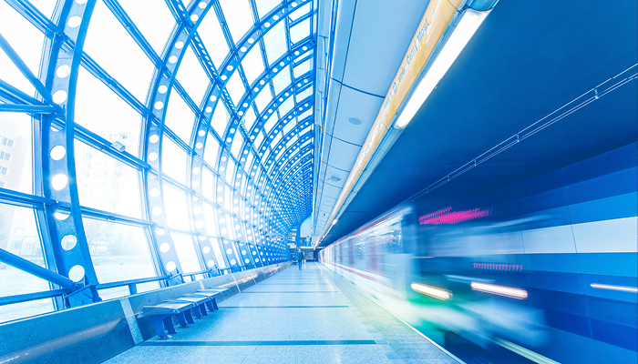 Moderner Bahnhof mit einer Glasfront und einem Zug in Bewegung