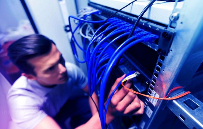 Mann vor Computer mit vielen Kabeln