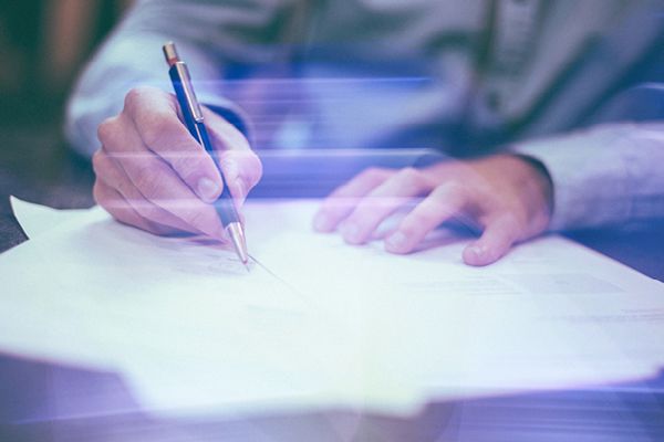 Ein Papier wird unterschrieben. Dies symbolisiert die Verlängerung der Zertifikate nach ISO 27001 und ISO 9001.