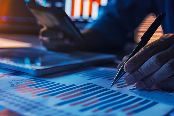 Person sitzt am Schreibtisch und überprüft ein Balkendiagramm